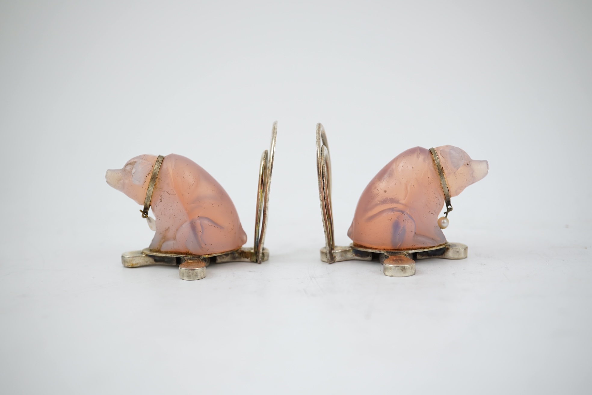 A cased pair of unusual Edwardian silver and pink glass mounted menu holders, by William Comyns, each modelled as a seated pig with collar